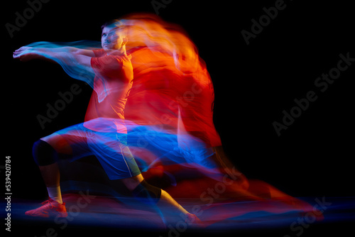 Fototapeta Naklejka Na Ścianę i Meble -  Athlete in motion. Young volleyball player in action isolated on dark background in neon mixed light. Fitness, sport, team, competition, championship, professional occupation