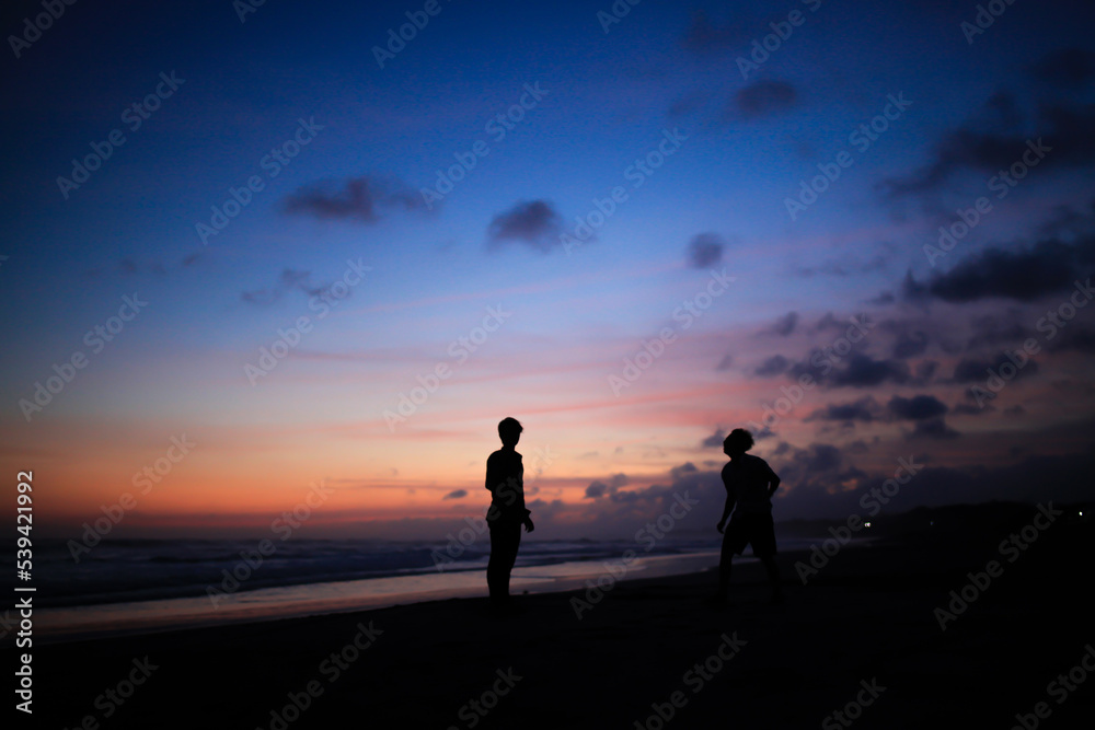 silhouette of two men playing on the beach