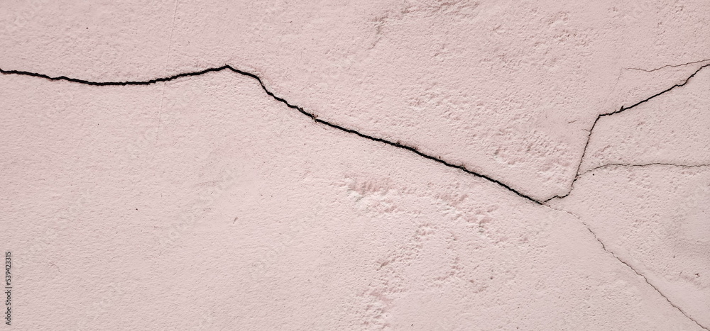 Obraz premium Old pink concrete that cracks buildings or walls leading to obvious crevices.This can cause wear and tear and cause concern or trouble for user. Weathered rough surface. Texture for background, design