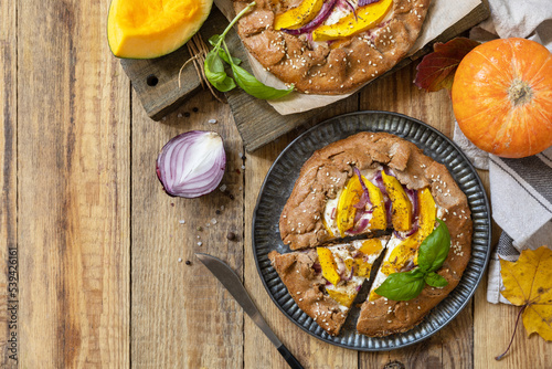 Homemade galette pie or crostata with pumpkin and ricotta cheese on rustic background. Thanksgiving day food. View from above. Copy space.