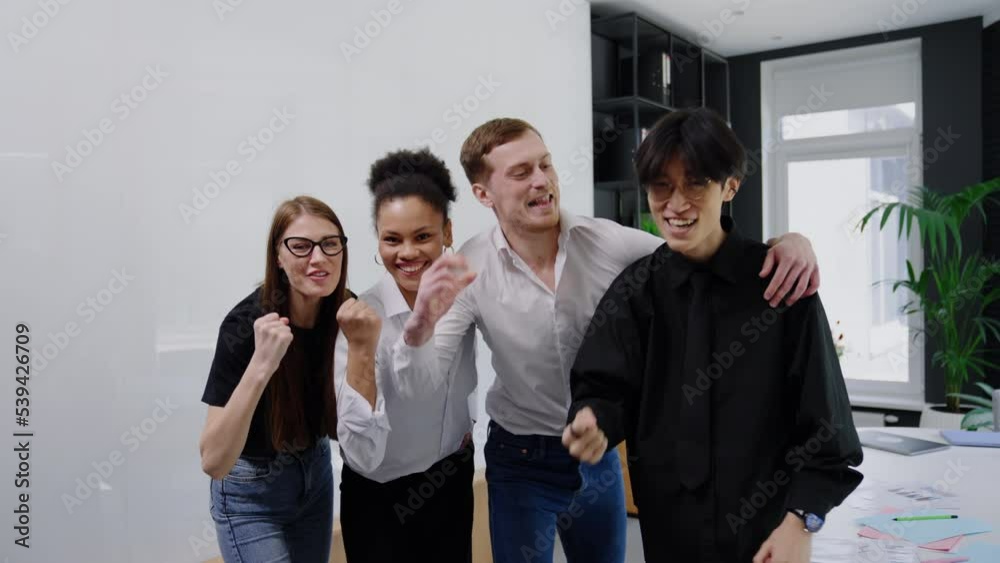 Multicultural team of office workers enjoys and look into the camera