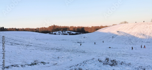 Obraz na płótnie Danish winter landscape with white fields and hills and children sledging in the