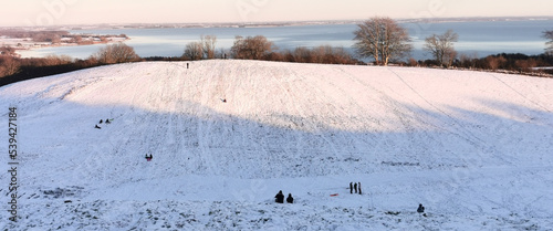 Billede på lærred Danish winter landscape with white fields and hills close to the sea and childre