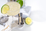 Sour alcoholic lime gin gimlet drink. Lemonade martini alcohol boozy cocktail garnished with lime, white background copy space