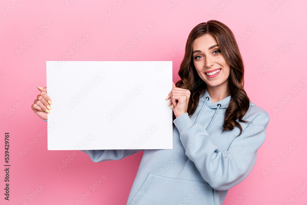 Portrait of cheerful positive lady hands hold empty space paper toothy smile isolated on pink color background Portrait of cheerful positive lady hands hold empty space paper toothy smile isolated on pink color background