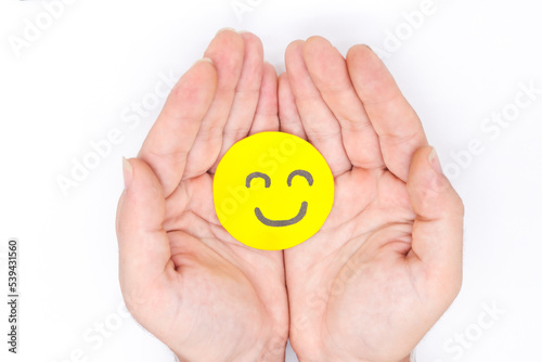 фотографія hand holding yellow paper happy faces on a white background