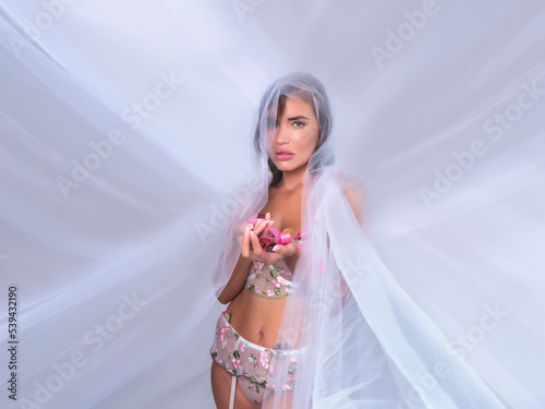 Sensual woman in lingerie standing under veil