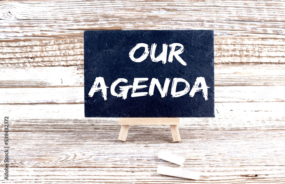 Obraz premium OUR AGENDA text on the Miniature chalkboard on wooden background