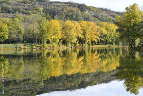 Fototapeta Naklejka Na Ścianę i Meble -  superbe plan d'eau avec ses arbres colorés de jaune et d'orange par une belle journée d'automne, se reflétant comme un miroir sur l'eau