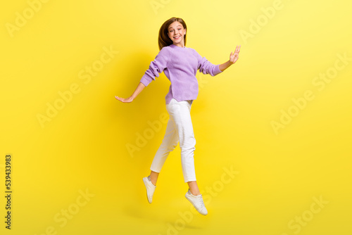 Full length photo of cute adorable lady wear stylish violet knitted pullover rejoice free time walking isolated on yellow color background