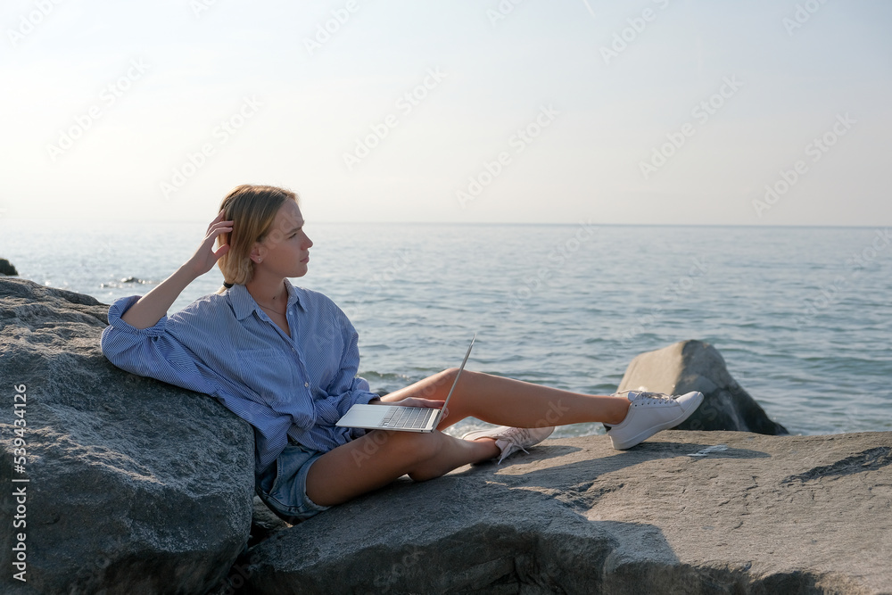 Remote work.Girl freelancer works remotely on the sea shore.workation, remote work,WFVH,Van Life vibes work from vacation home,work travel,remotely work.Travelling.Work from vacation remotely