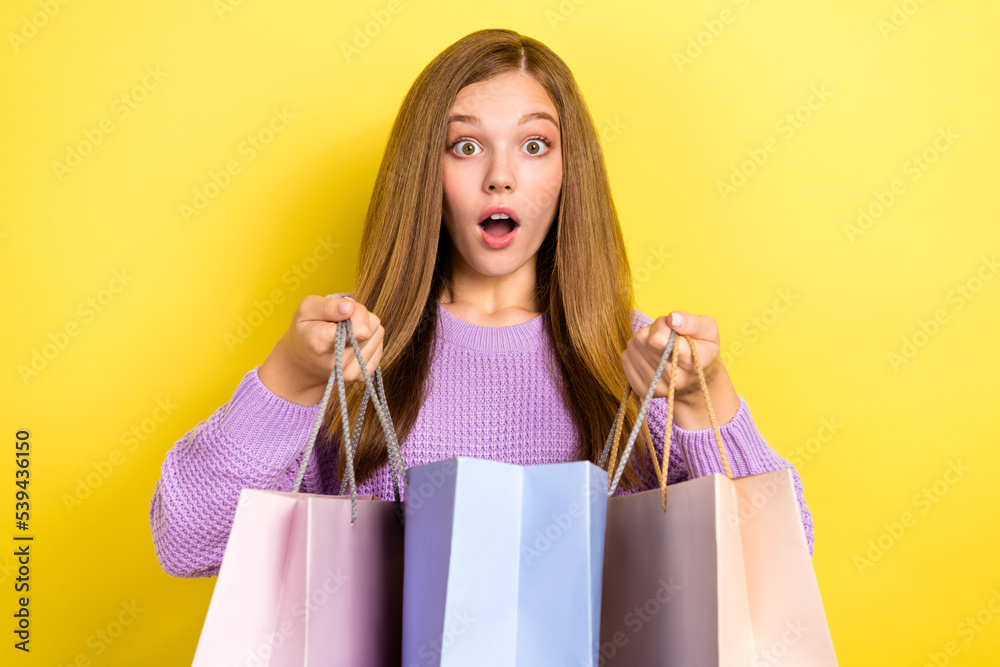 Closeup portrait photo of young excited girl teenager open mouth surprised hold stack package gift season sale zara shopping isolated on yellow color background