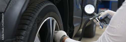 Bilde på lerret Automechanic pumping up tires with special instrument at work