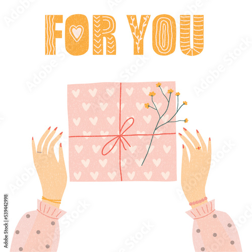 Gift box and female hands, top view. Women's hands are wrapping a gift. The box is decorated with a bouquet of flowers.