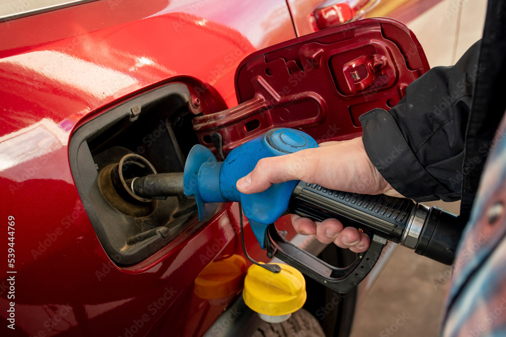 A man hand holding pump filling gasoline. Pumping petrol into the tank. A car refuel on gas station
