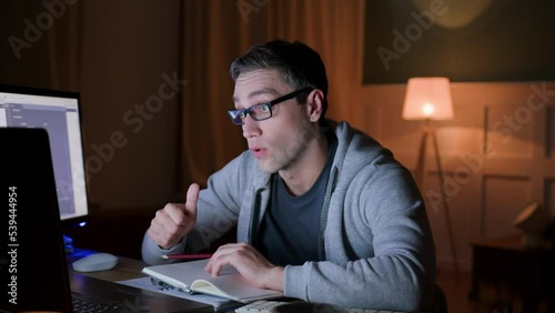 young man in eyeglasses on workplace at home, has online video call with coworkers using laptop. male applicant pass online interview using web cam. student on examination of online education. 