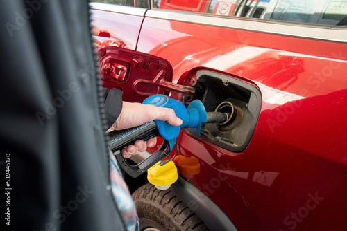 A man hand holding pump filling gasoline. Pumping petrol into the tank. A car refuel on gas station © Daria Nipot
