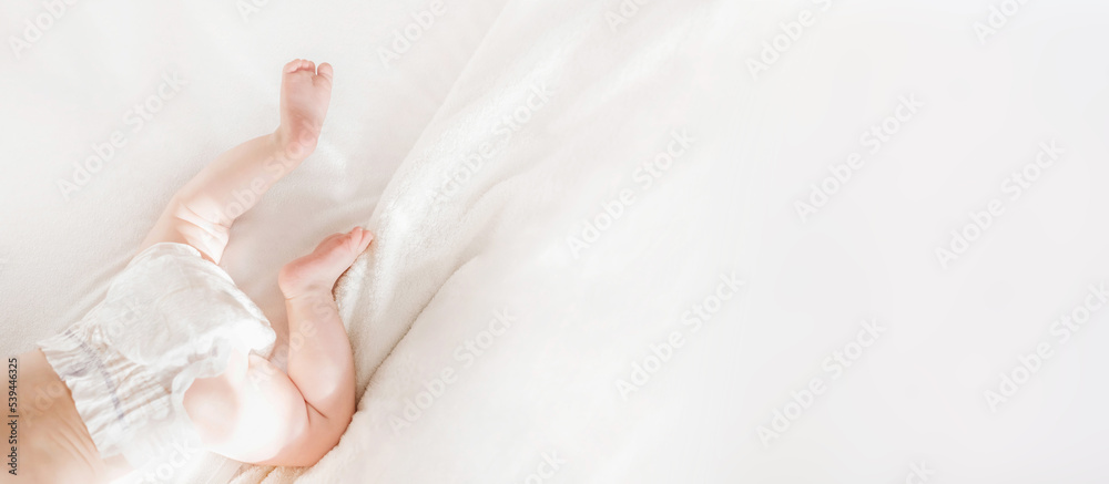 Baby in a diaper lies on a white bed. top view. copy space Baby in a diaper lies on a white bed. top view. copy space