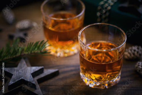 Whiskey, brandy or liquor shot and Christmas decorations on wooden background. Winter holidays concept.