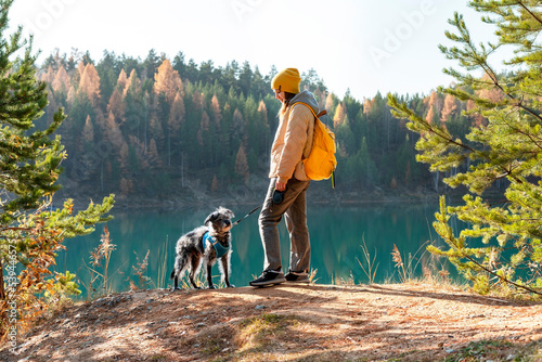 Photography Young tourist woman with yellow backpack walking with mixed breed Bedlington Whi