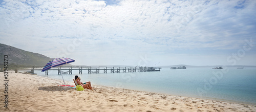 Couple sitting and relaxing on sunny, sandy ocean beach photo