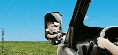 A little boy is playing near a car