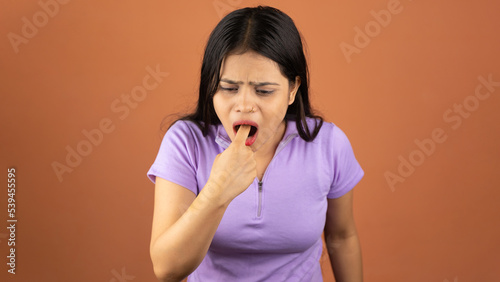 Young sick woman, annoyed frustrated, disgusted, fed up, sticking fingers in her throat, about to throw up, Isolated color background