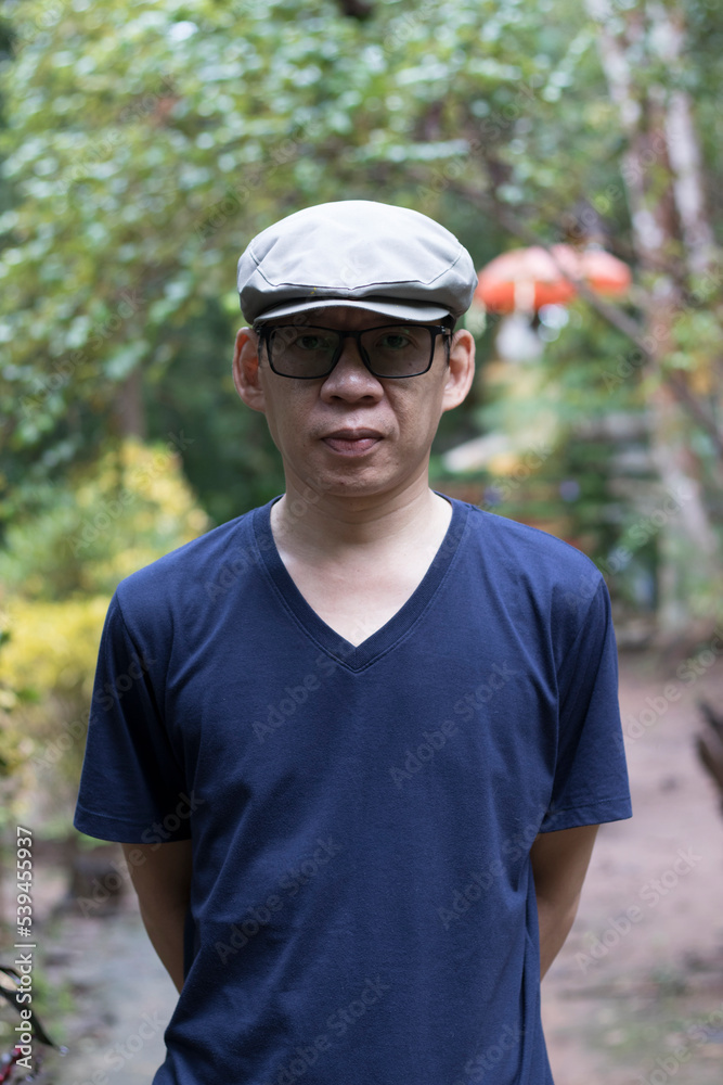 outdoor portrait of an adult man isolated on blur background, standing in a navy blue t-shirt, smiling and looking straight at the camera. outdoor portrait of an adult man isolated on blur background, standing in a navy blue t-shirt, smiling and looking straight at the camera.