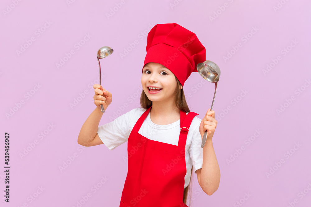 A girl in a cook's costume holds a ladle in her hands and is going to cook soup, the child dreams of becoming a cook. A girl in a cook's costume holds a ladle in her hands and is going to cook soup, the child dreams of becoming a cook.