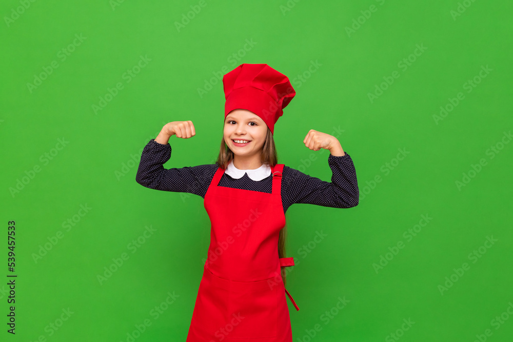 A teenage girl has put on a chef's uniform and is very happy that she will cook breakfast, a child in the form of a cook on an isolated green background. A teenage girl has put on a chef's uniform and is very happy that she will cook breakfast, a child in the form of a cook on an isolated green background.