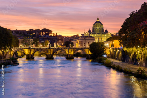 St. Peter's basilica dome and St. Angel bridge over Tiber river at sunset in Rome, Italy