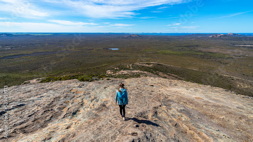 brave backpacker girl descends from frenchman peak in cape le grand national park in western australia, hiking and climbing a mountain with a backpack