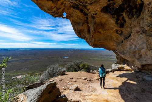 a girl stands in a cave on frenchman peak in cape le grand national park in western australia, hiking overlooking the ocean and paradise beaches