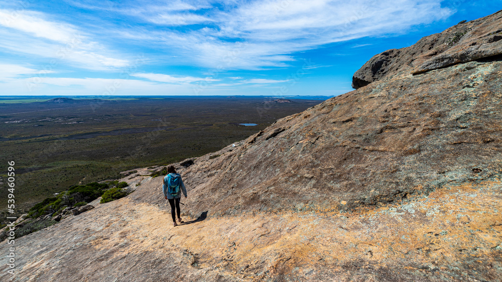 brave backpacker girl descends from frenchman peak in cape le grand national park in western australia, hiking and climbing a mountain with a backpack