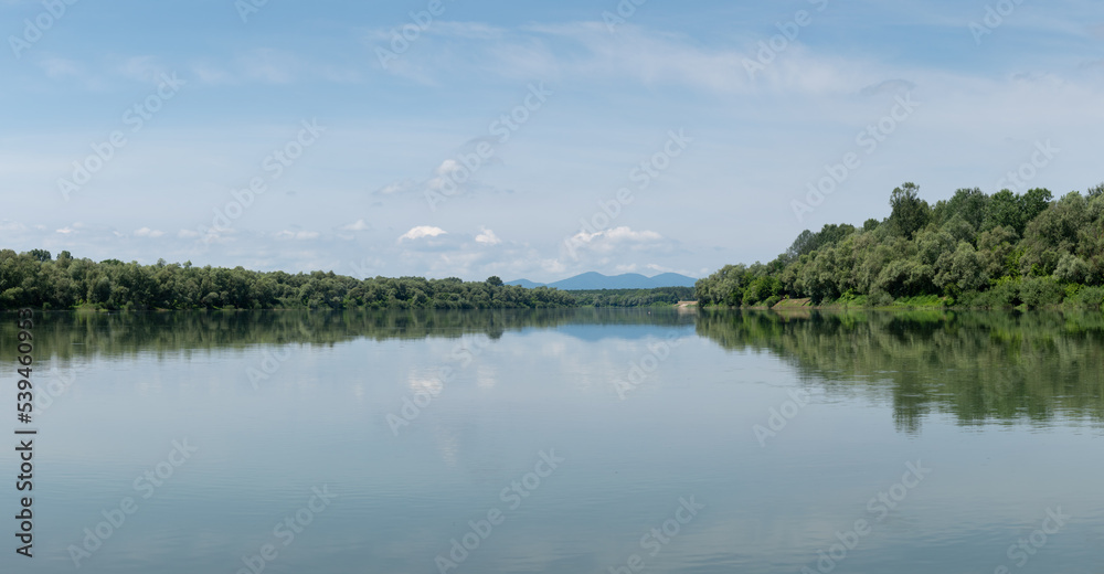 Fototapeta premium Landscape of Sava river and distant mountain Motajica silhouette in haze, during sunny summer day