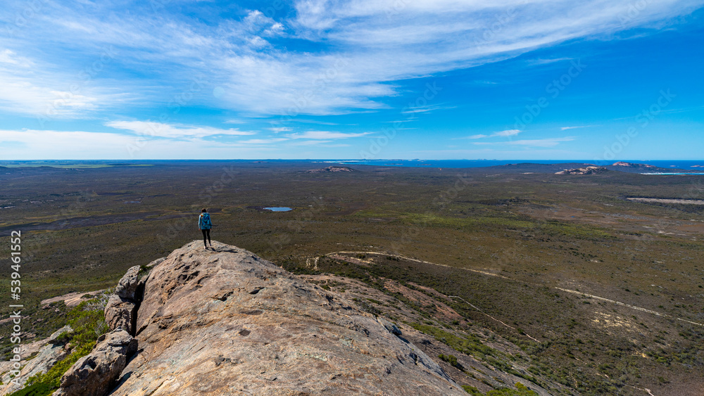 brave backpacker girl celebrates summiting frenchman peak in cape le grand national park in western australia, hiking and climbing the mountain with her backpack