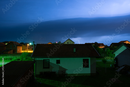 Lightning glow in clouds above suburbs at night, thunderstorm at night