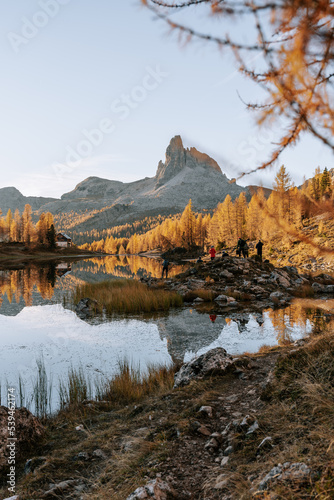 Erste Sonnenstrahlen am Lake Fedare / Lago di Federa in den Belluner Dolomiten zum Sonnenaufgang. Es ist Herbst und der Wald am See leuchtet gelb. Sonnenaufgang Dolomiten 10