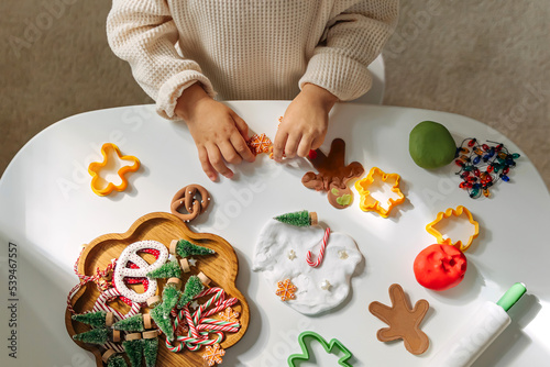 Child hands creating Christmas crafts. Child playing with play dough and Christmas decorations. Holiday Art Activity for Kids. Sensory play for toddlers. photo