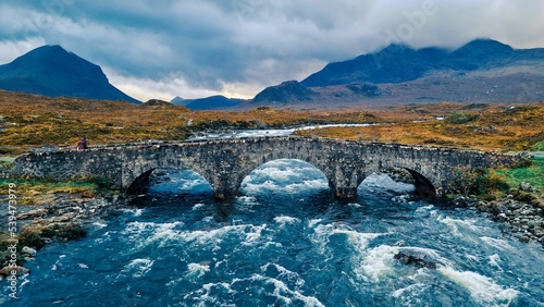 Landscape view of the Sligachan Old Bridge and flowing river, cloudy, gloomy sky background photo