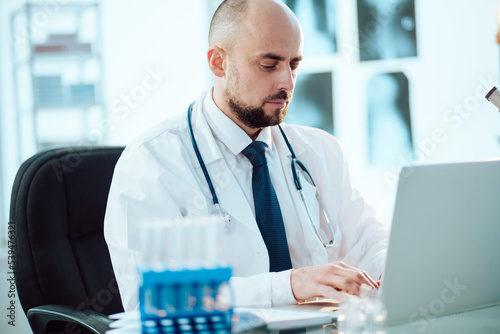 scientist works on a laptop while sitting at a table in a medical laboratory.