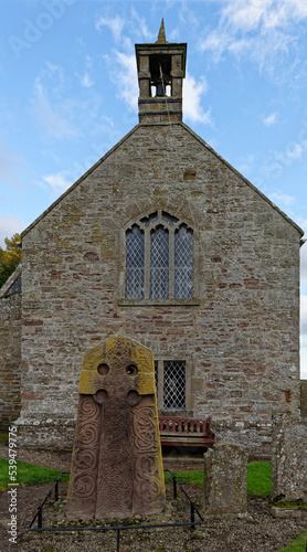 The West View of the Aberlemno 2 Sculptured Stone in the Kirkyard of the local church, with its Celtic Cross, beneath the Bell Tower. photo