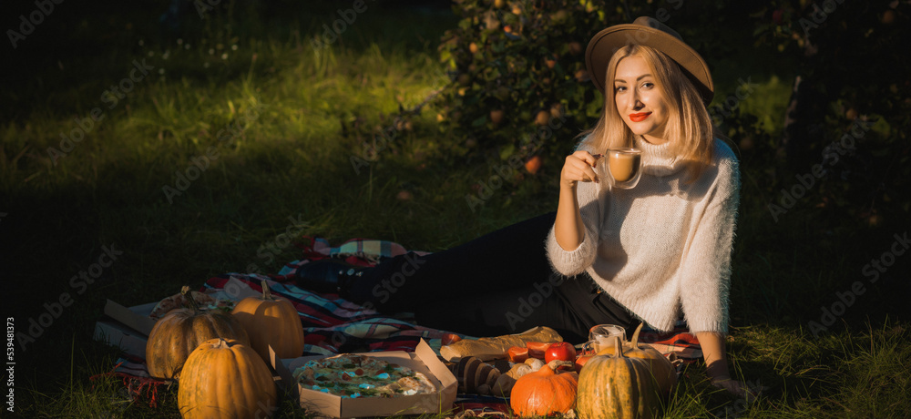 Autumn vibe concept. Stylish blonde woman at autumn garden with good mood. Lady with pretty accessorize and casual style on a nature