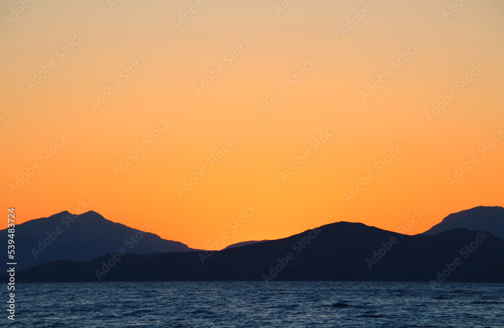 Orange sky during sunset over mountains at the sea (Tigaki, Kos Island, Greece)