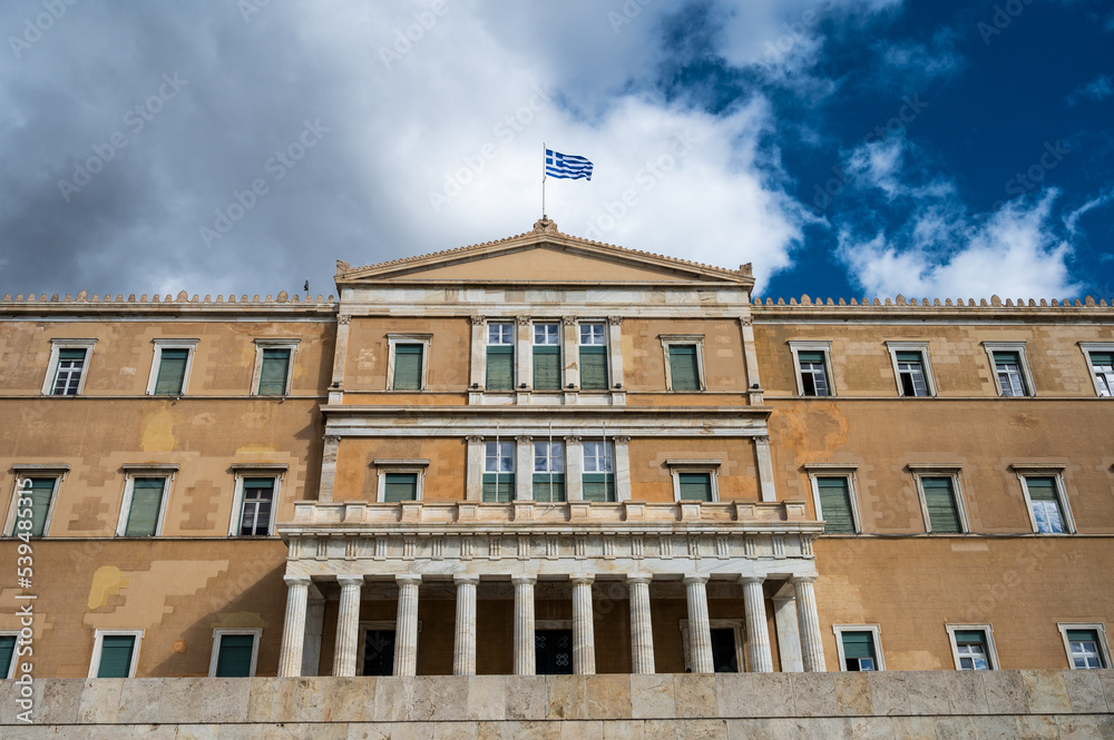 View of the facade of the Greek Parliament with the Greek flag waving.