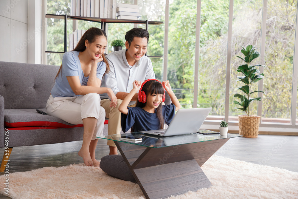 Children education and home school concept : Young asian father and mother see little daughters' study. Excited smiling small child girl enjoying learning and reading with pleasant dad and mom at home Children education and home school concept : Young asian father and mother see little daughters' study. Excited smiling small child girl enjoying learning and reading with pleasant dad and mom at home
