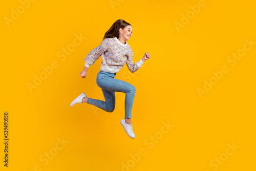 Full length profile photo of funny young lady run wear jeans sneakers isolated on vivid background © Tetiana