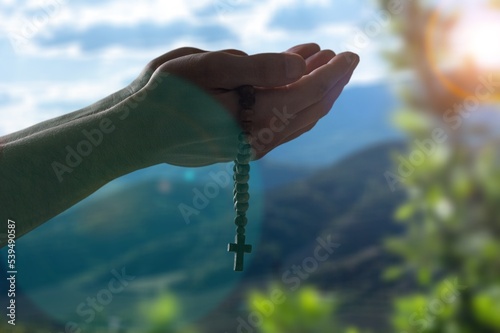 Hands with religious cross for pray outdoors