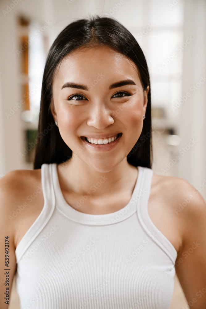 Young beautiful smiling happy asian woman in white sleeveless t-shirt Young beautiful smiling happy asian woman in white sleeveless t-shirt