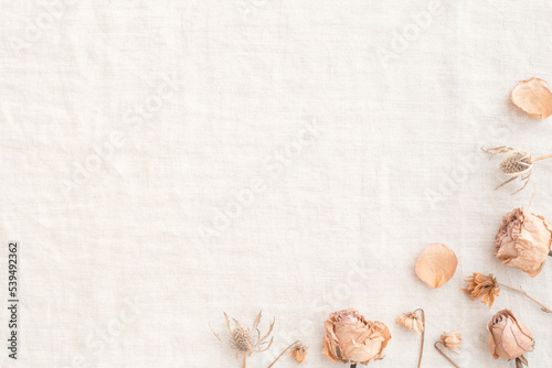 Decorative frame of beige pink roses with dried flowers placed on a light burlap background